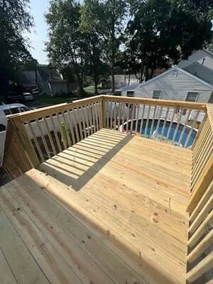 Newly constructed pressure-treated wood deck with railings and vertical balusters