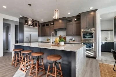 Modern kitchen with dark wood cabinets, white quartz counters, stainless steel appliances, and island seating