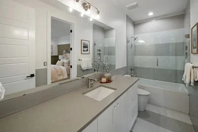 Master bathroom with white cabinetry, quartz counters, frameless glass shower, and tile flooring