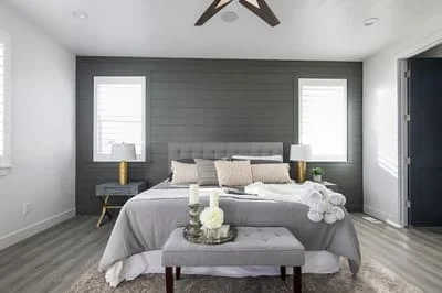 Master bedroom with charcoal gray shiplap accent wall, white walls, and ceiling fan