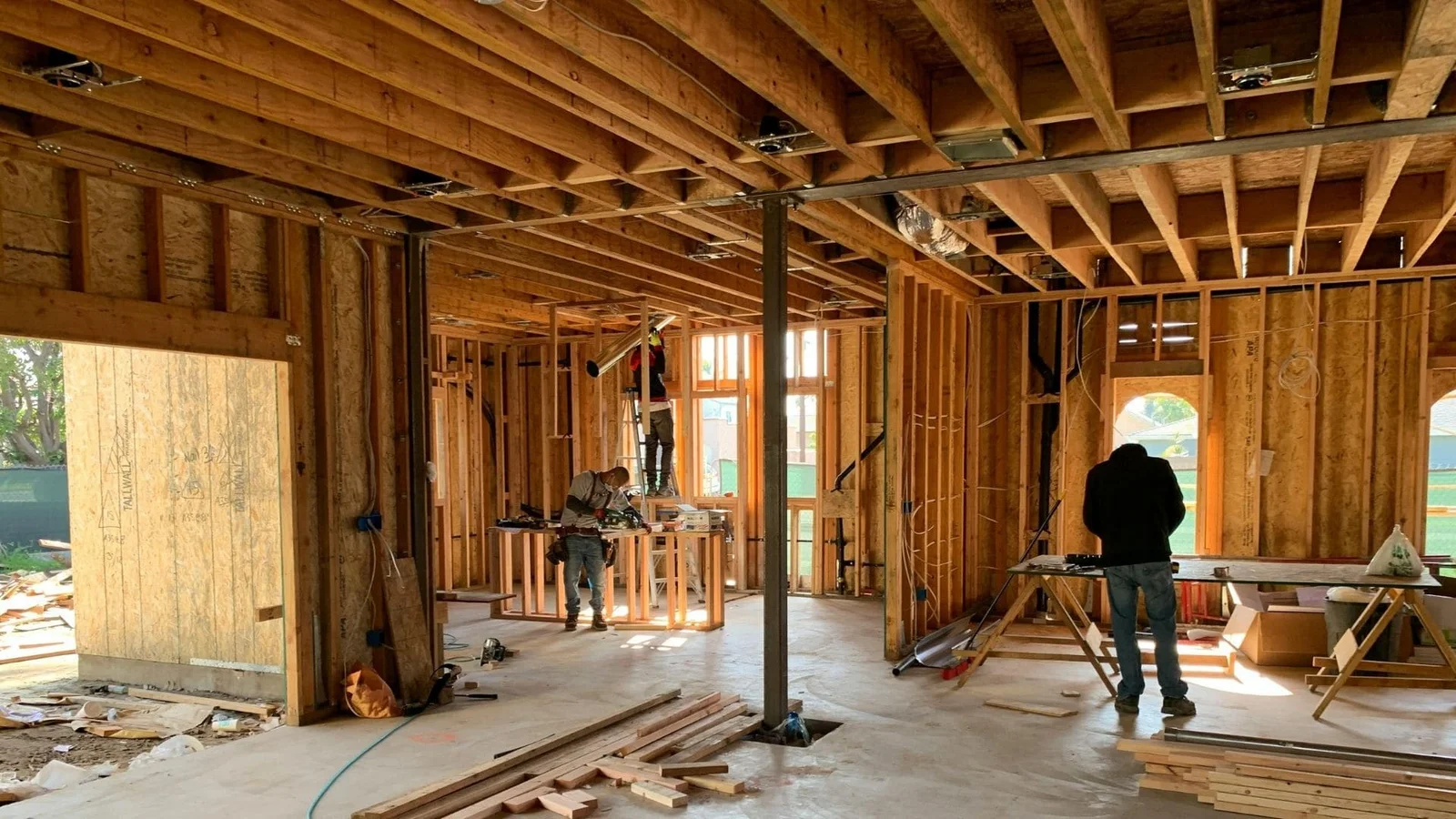 Interior framing with wooden joists, beams, studs, concrete floor, and window openings during construction