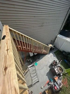 Newly constructed pressure-treated wood deck with railings and balusters against metal siding